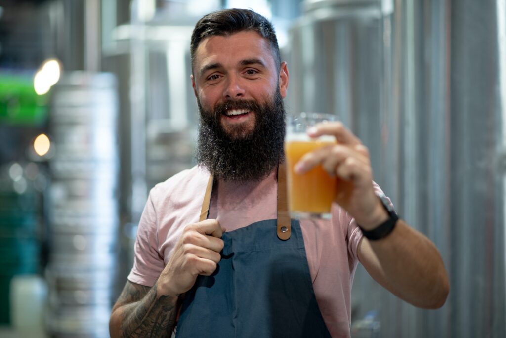 Bearded man examining the quality of craft beer at brewery