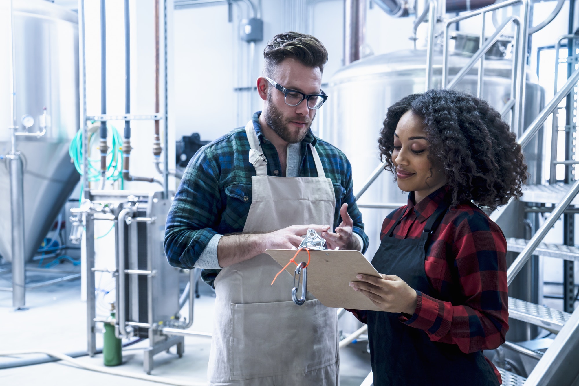 Colleagues in brewery looking at clipboard smiling